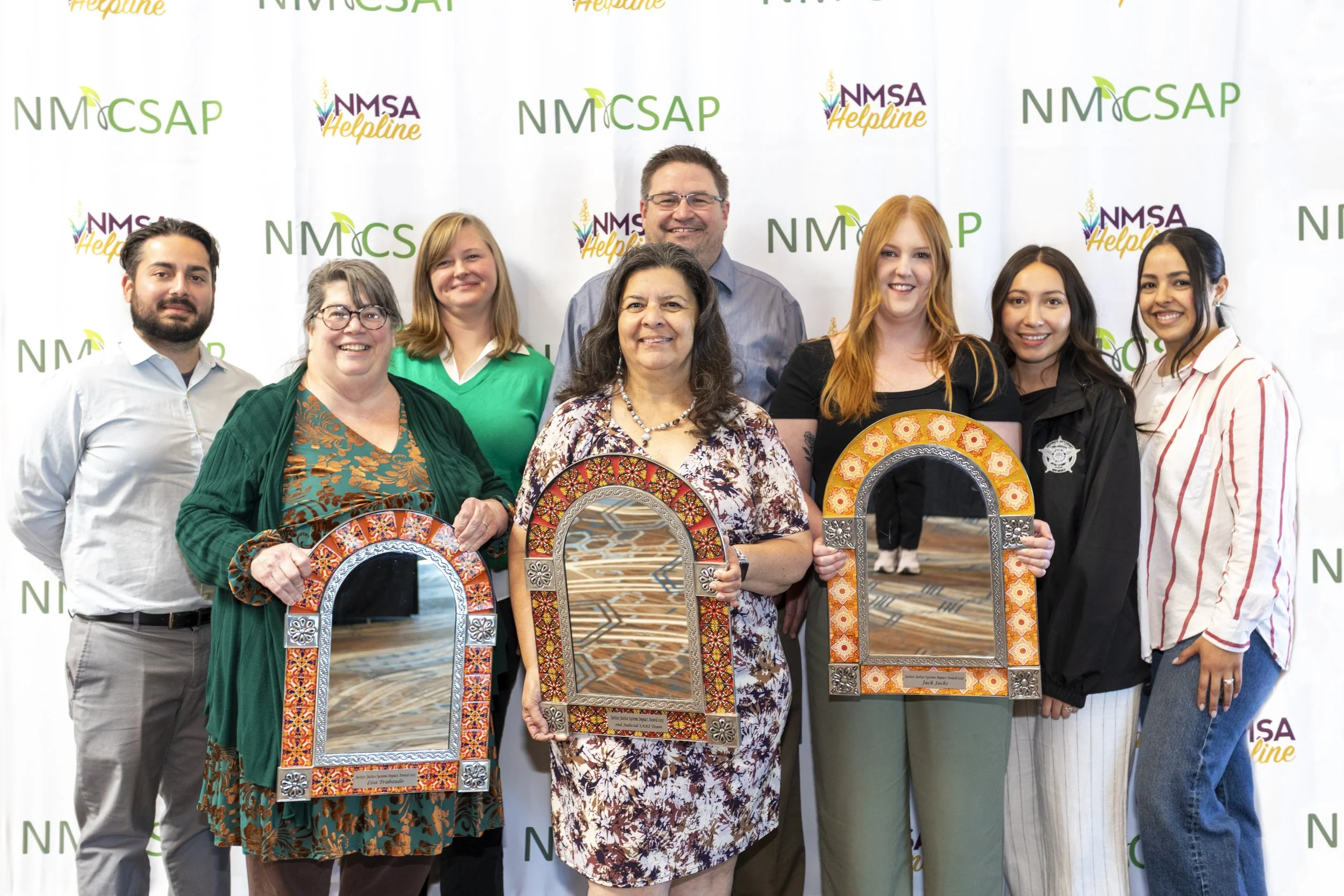 A group of people holding three awards