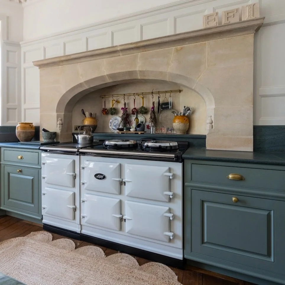 A wall of Pale green storage cupboards with an open doorway shoeing the kitchen beyond