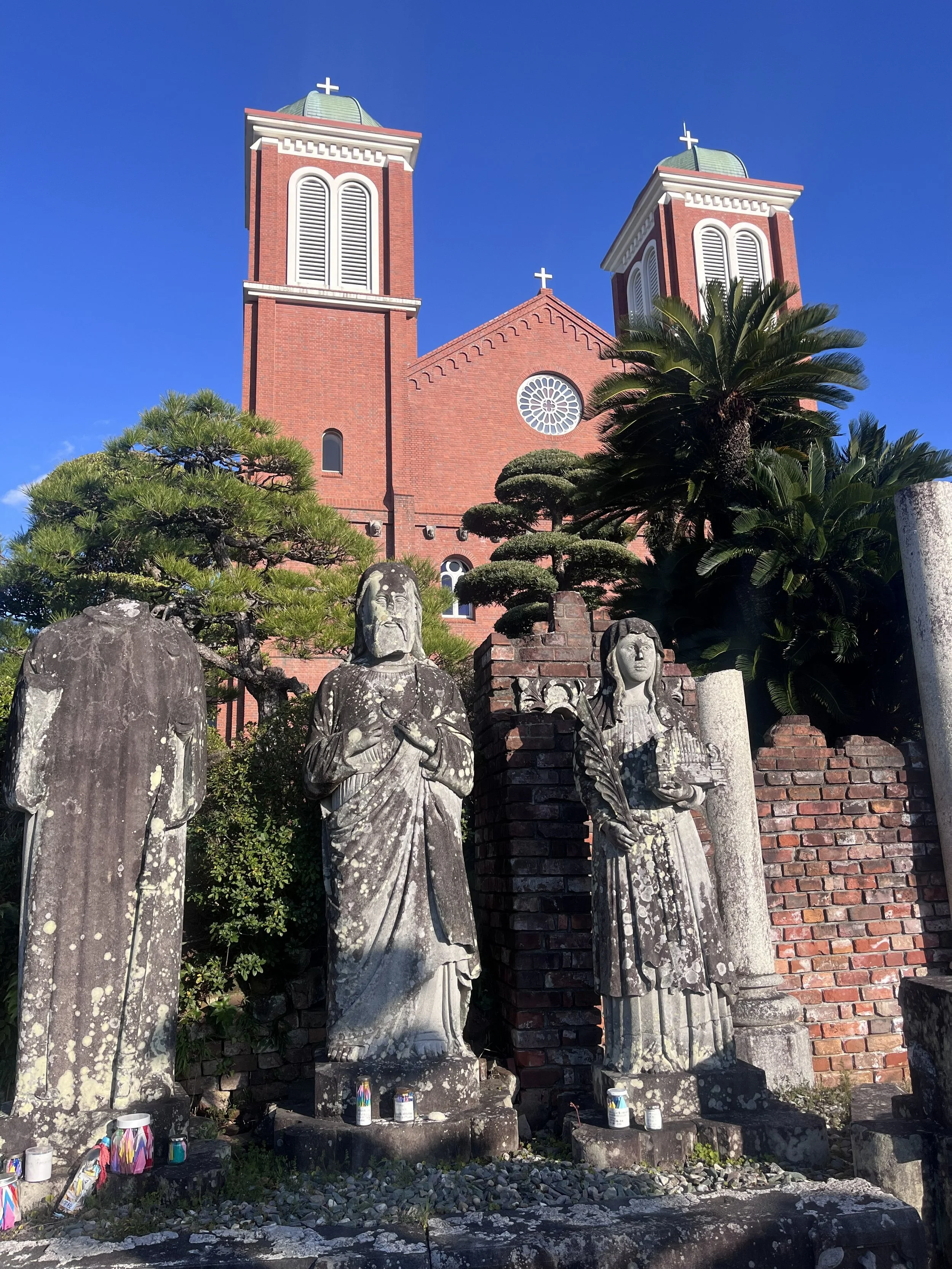 původní sochy z Urakami katedráli s její rekonstukcí v pozadí, Nagasaki