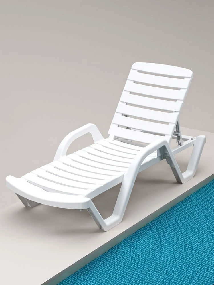 A white sunbed sitting next to a pool.