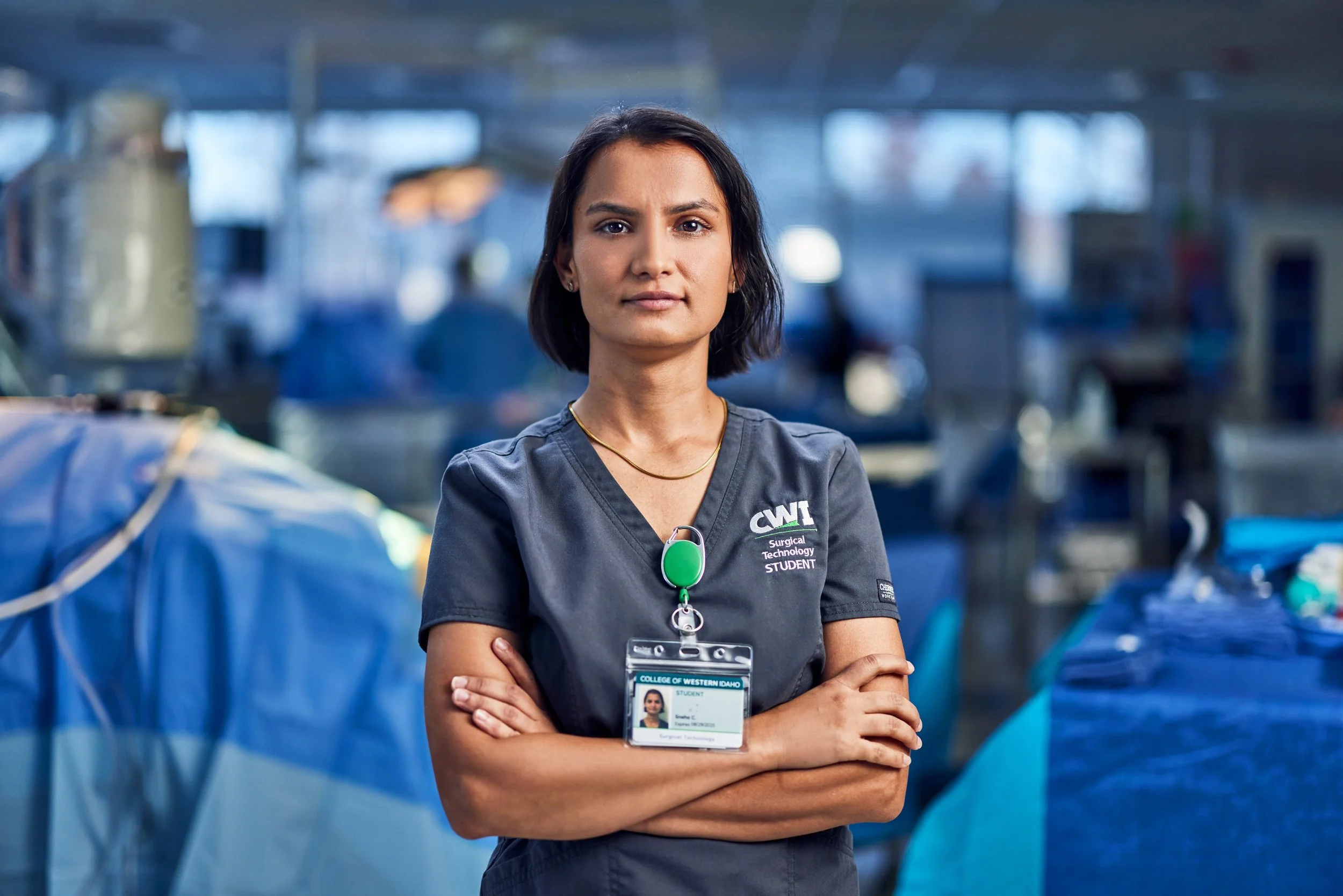 Person in surgical scrubs with crossed arms in a medical training facility.