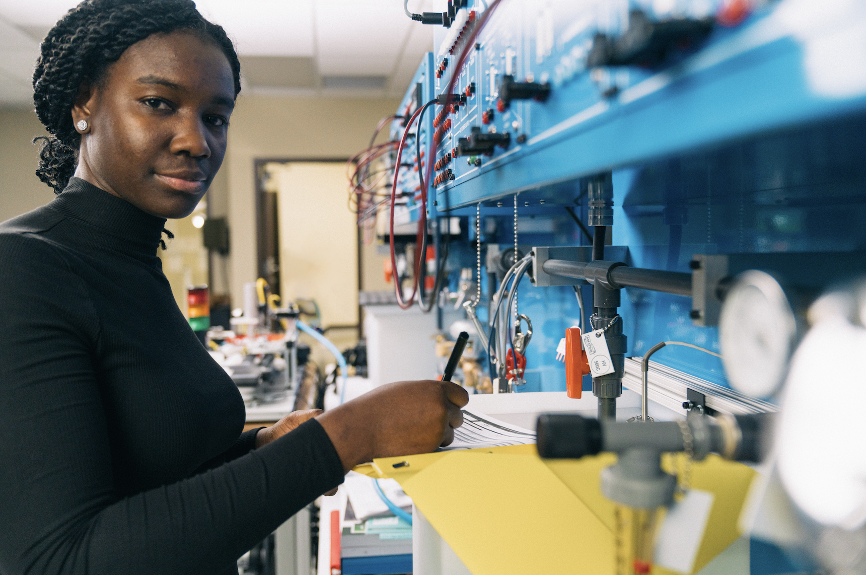 Person in a laboratory setting with blue equipment, writing on a document.