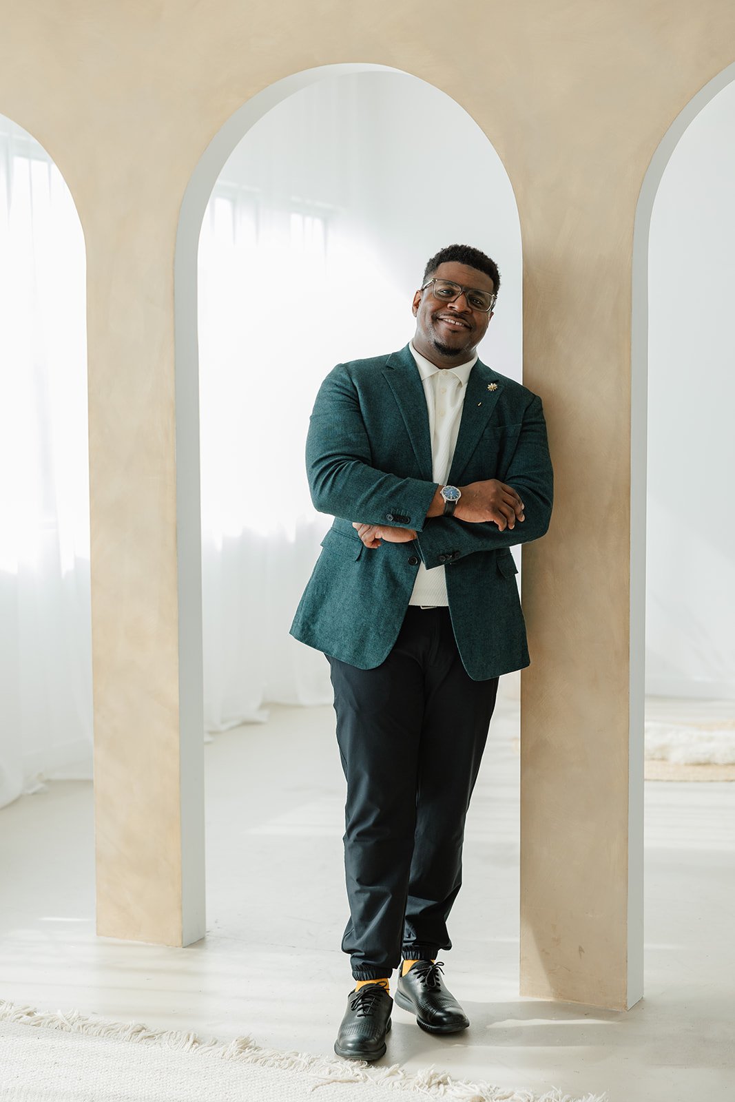 Smiling man wearing a brown jacket against a white background.