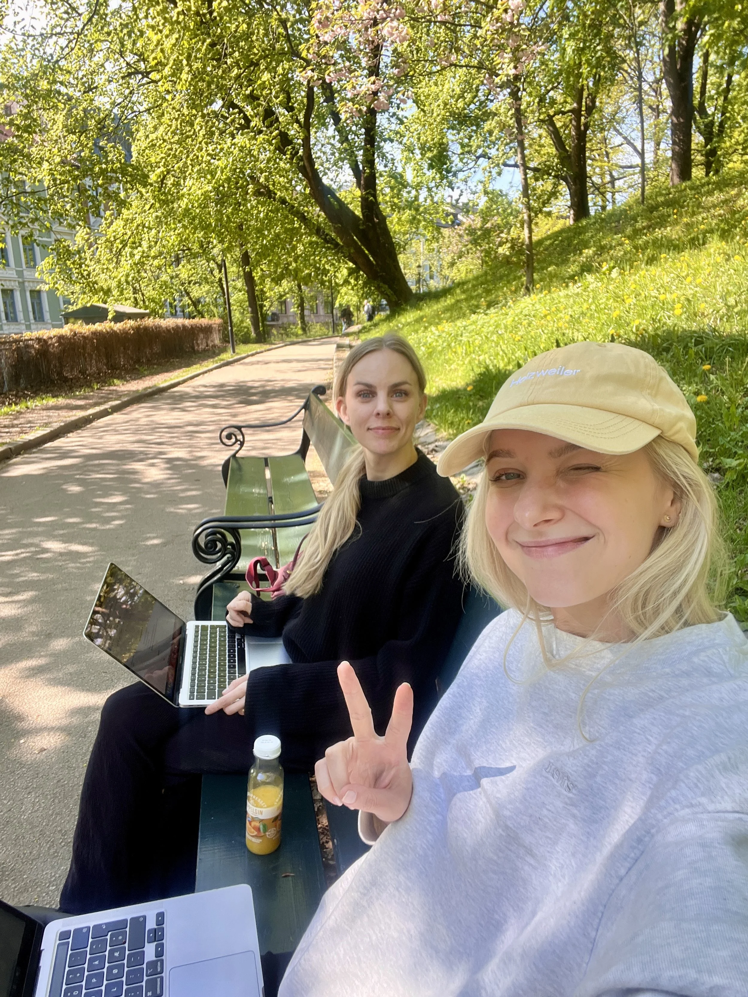 to kvinner sitter på en benk i sola