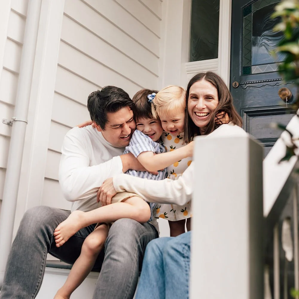 Family group hug on stairs of their home in Kerikeri