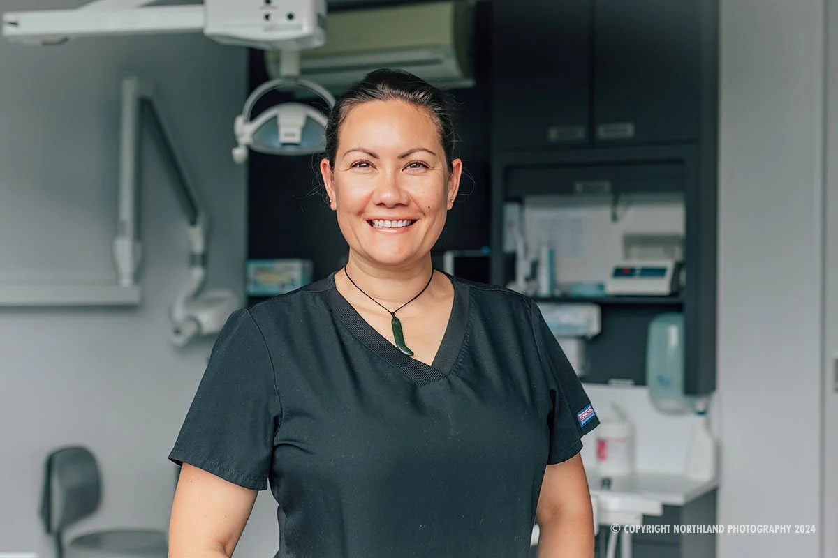 Maori nurse with pounamu and hair in bun smiling at camera