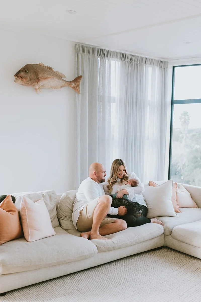 Newborn photoshoot with mother father and baby in bright and airy home with neutral couch and cushions