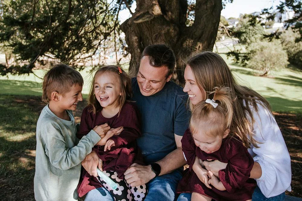 Family photo in nature with two daughters and son laughing
