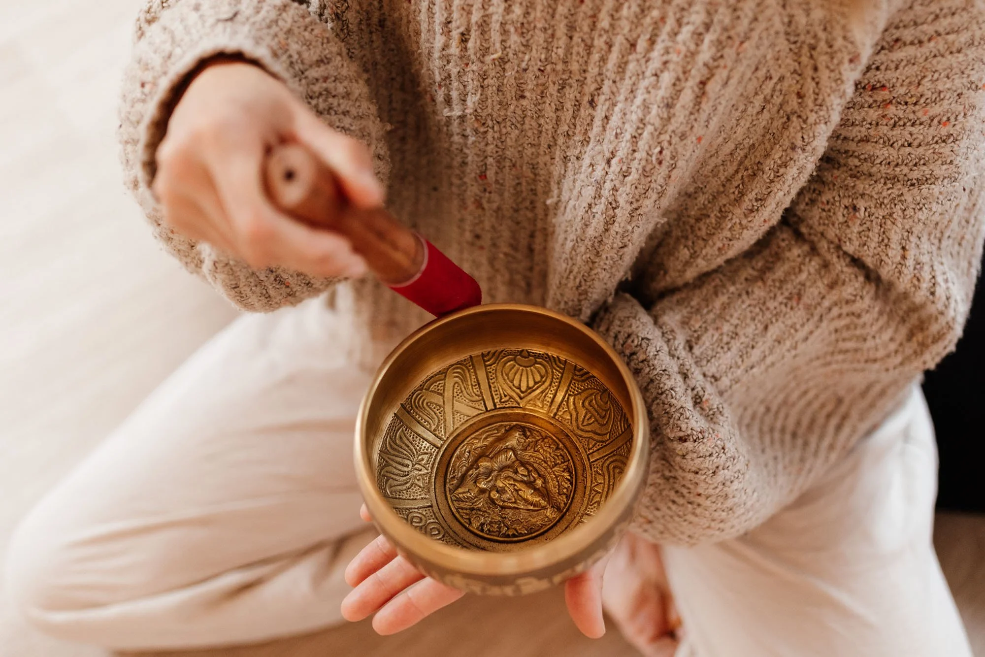 Yoga teacher sitting on ground with singing bowl