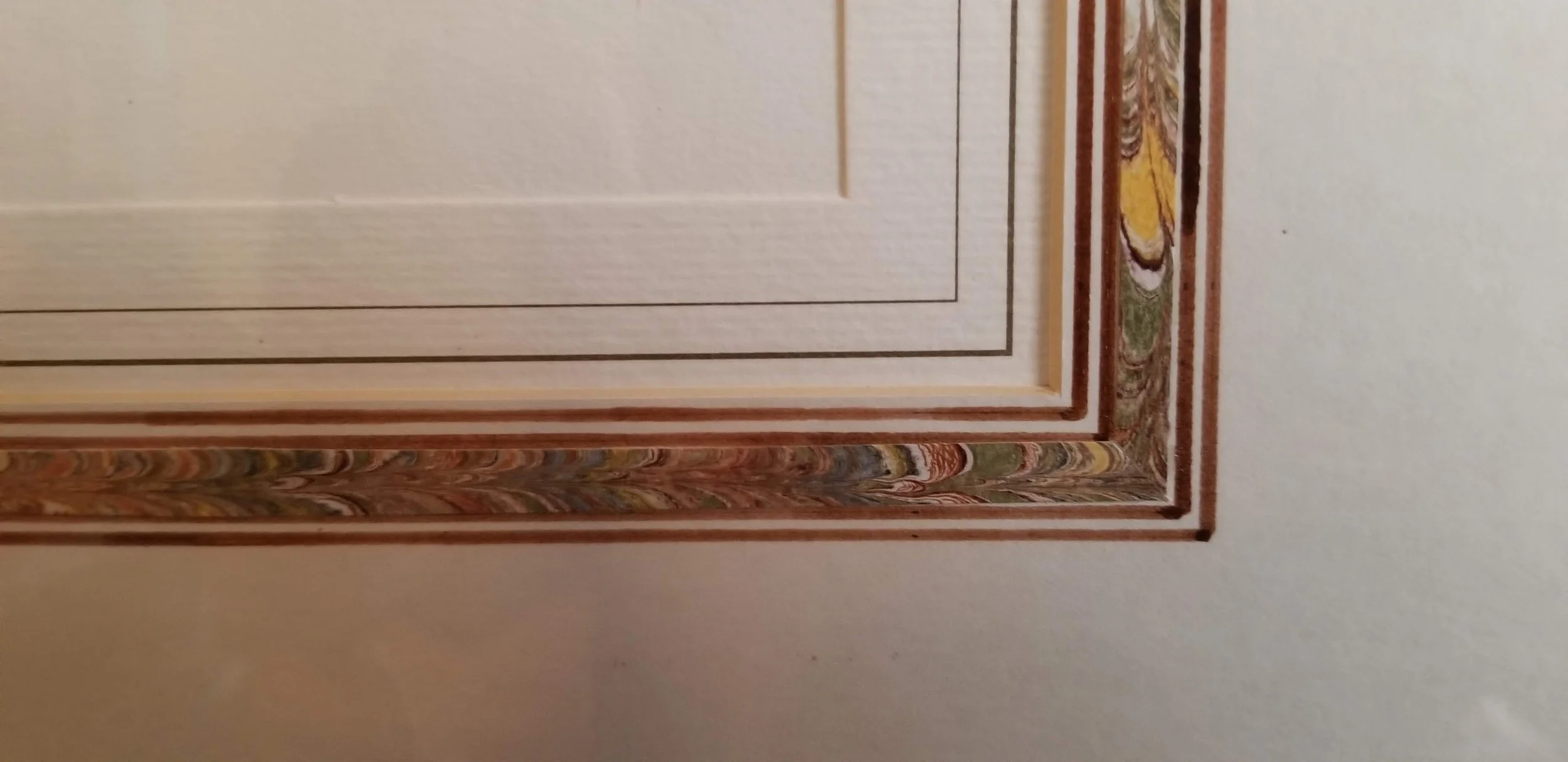Close-up of a door frame with ornate decorative trim and molding on a white wall.