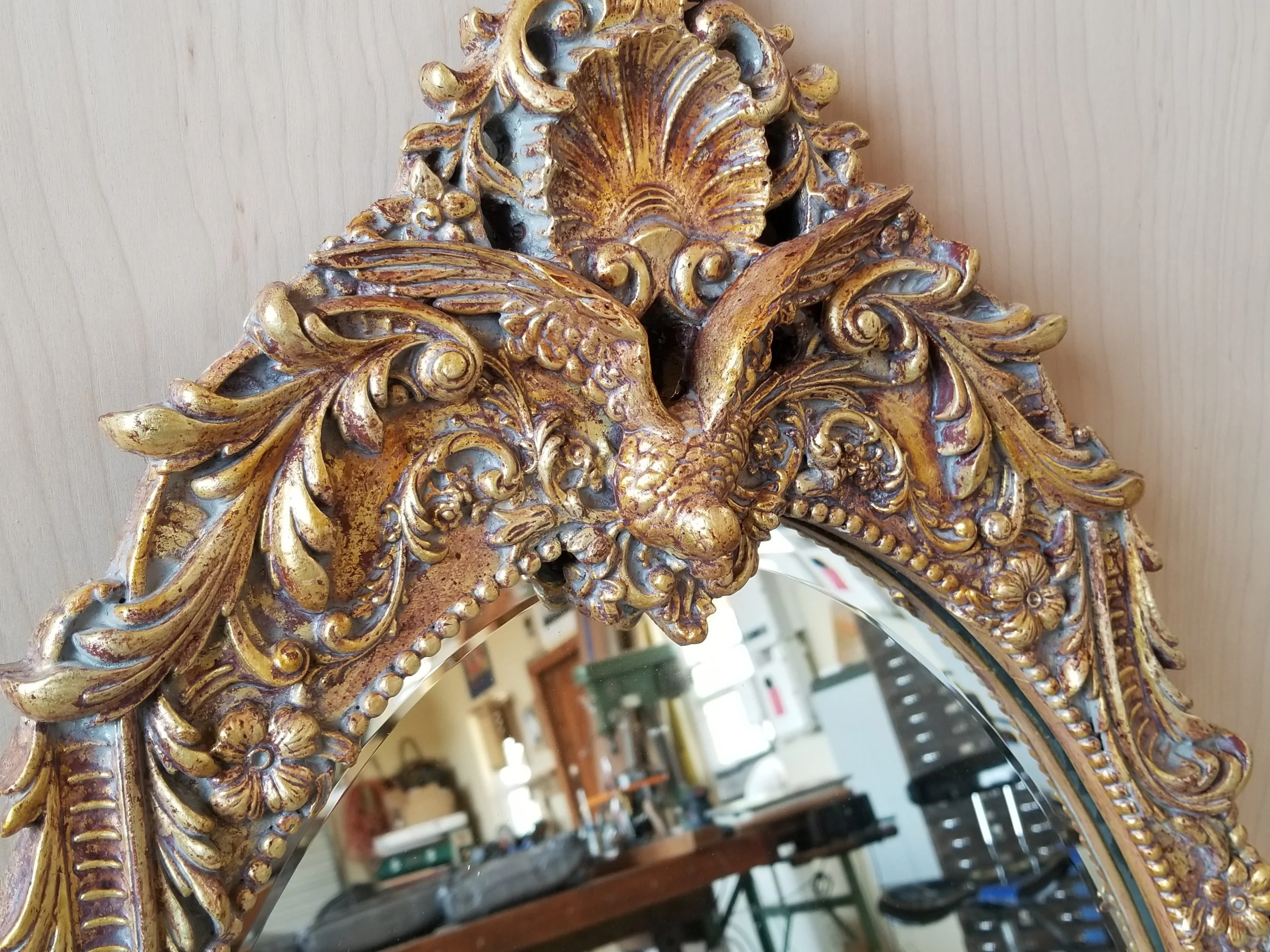 Close-up of an ornate gold and blue decorative element, possibly part of furniture or a framed mirror, with intricate floral and shell motifs.