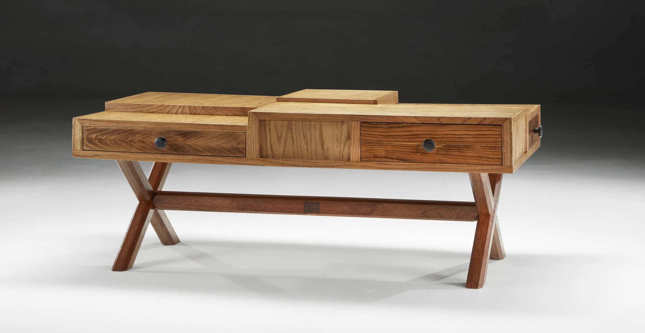 A wooden table with drawers and adjustable wooden legs against a dark background.