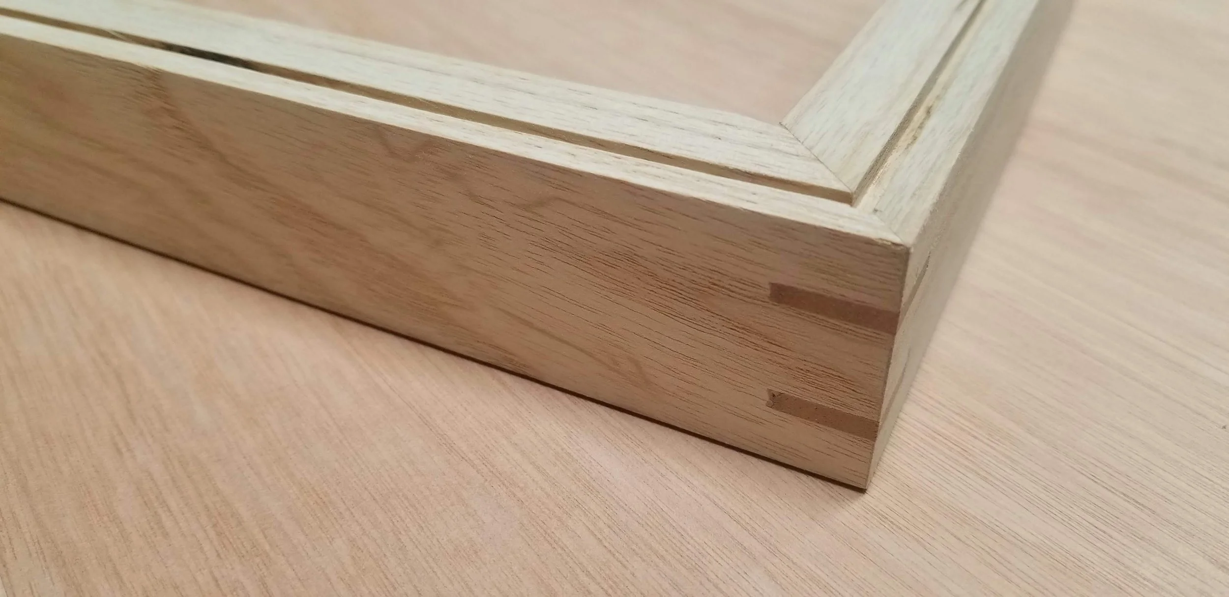 Close-up of a wooden picture frame resting on a wooden surface.