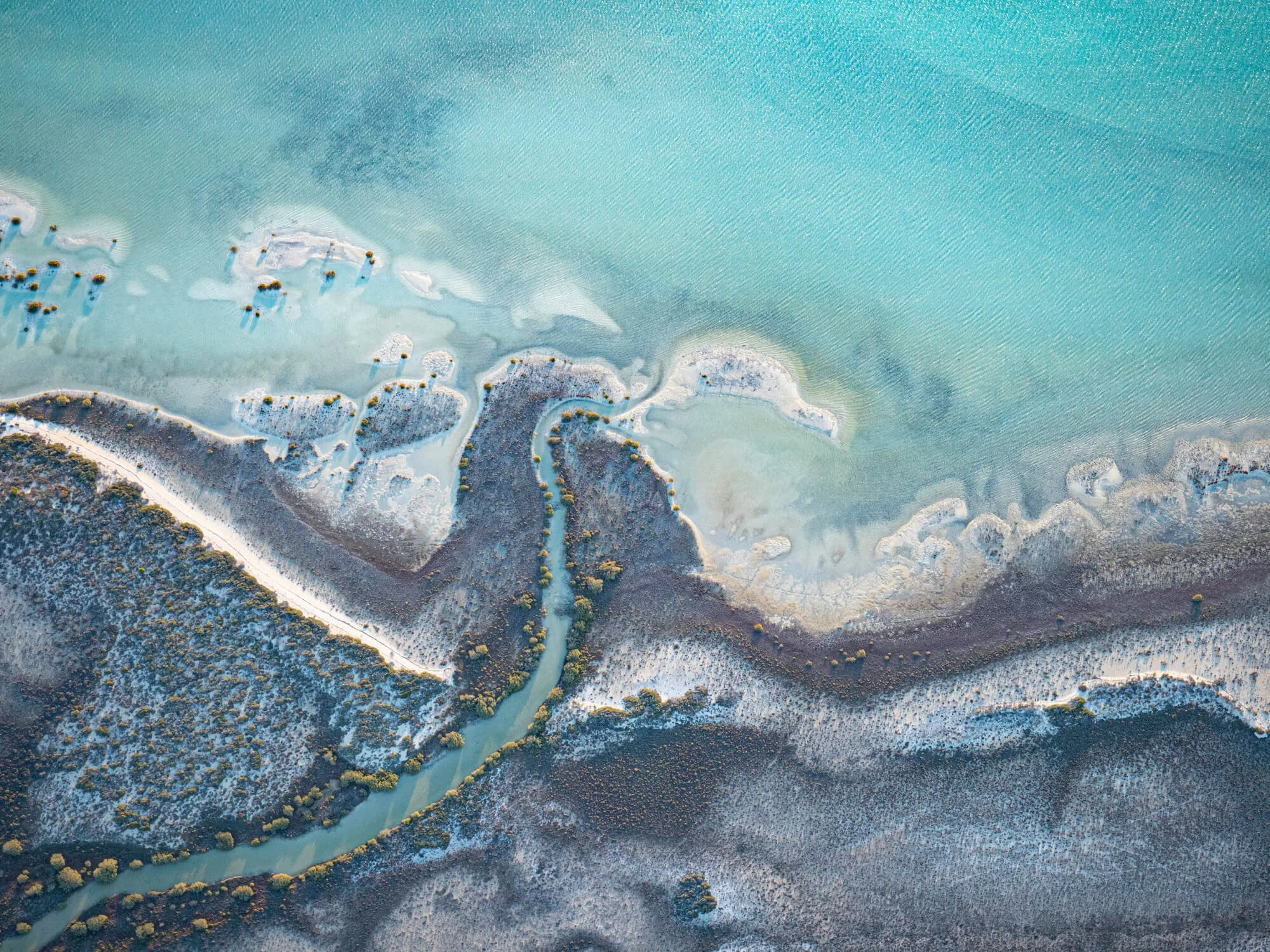 Aerial view of a river flowing through a landscape with small islands and trees.