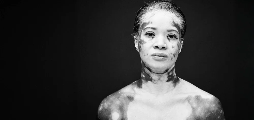 Black and white studio portrait of a woman, shoulders bare, on a black background, licensed by Dove