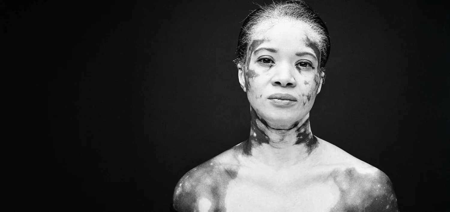 Black and white studio portrait of a woman, shoulders bare, on a black background, licensed by Dove