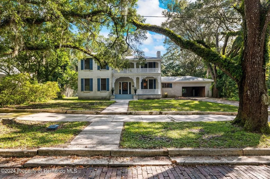 An old white historical home in south Brooksville Florida with moss covered oaks