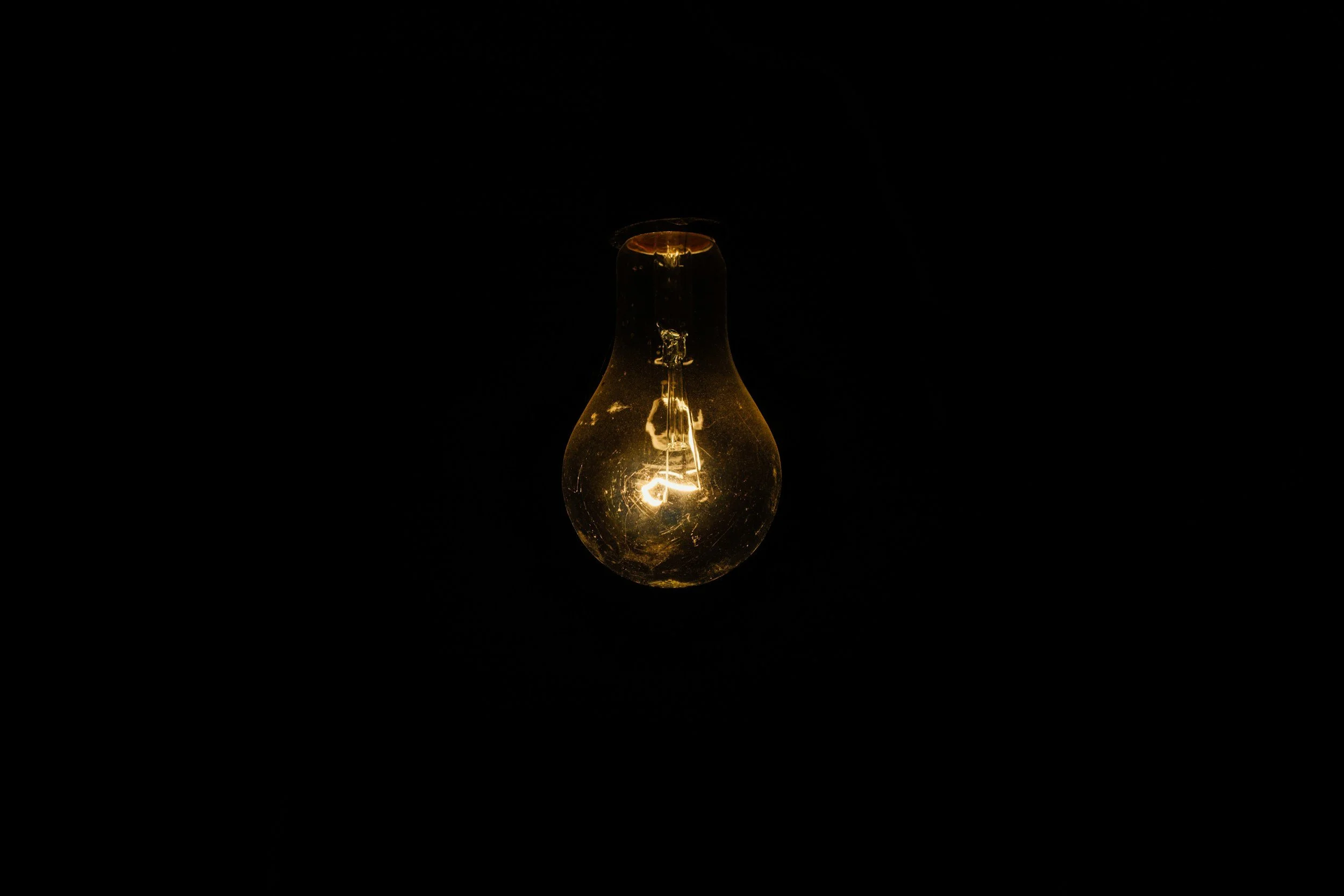 A glowing light bulb hanging against a dark background.