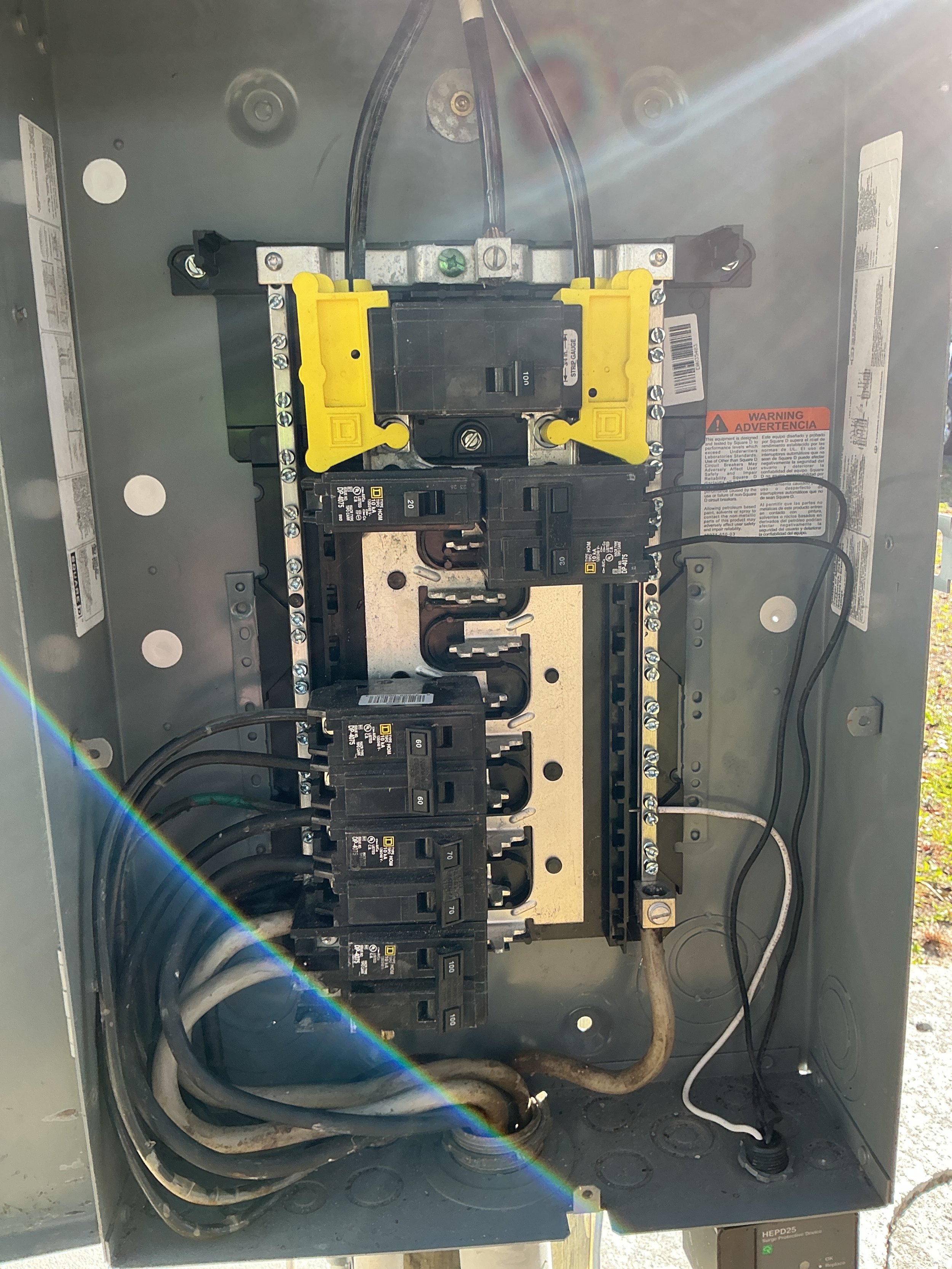 Open electrical panel with circuit breakers and wiring inside a metal box.