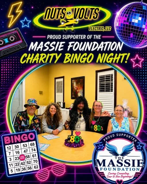 Group of five people sitting at a table with a bingo card on it, celebrating at a charity bingo night event hosted by Nuts Volt Electric LLC, supporting the Massie Foundation. Neon-themed decorations include a disco ball, stars, lightning bolt, cassette tape, and sunglasses graphic.