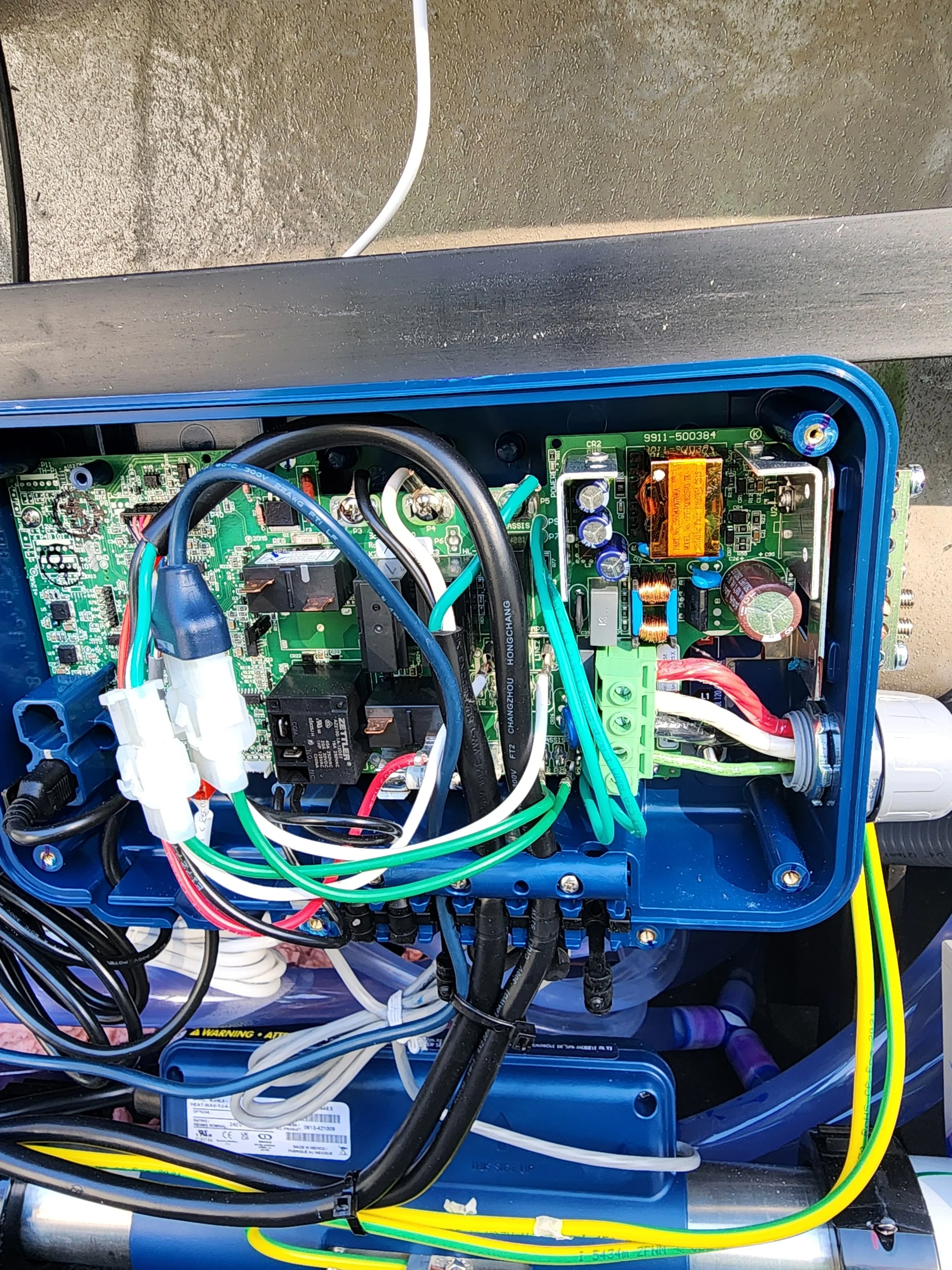 Close-up of the internal electronic circuit board inside a blue electrical enclosure, showing multiple wires, connectors, and electronic components.