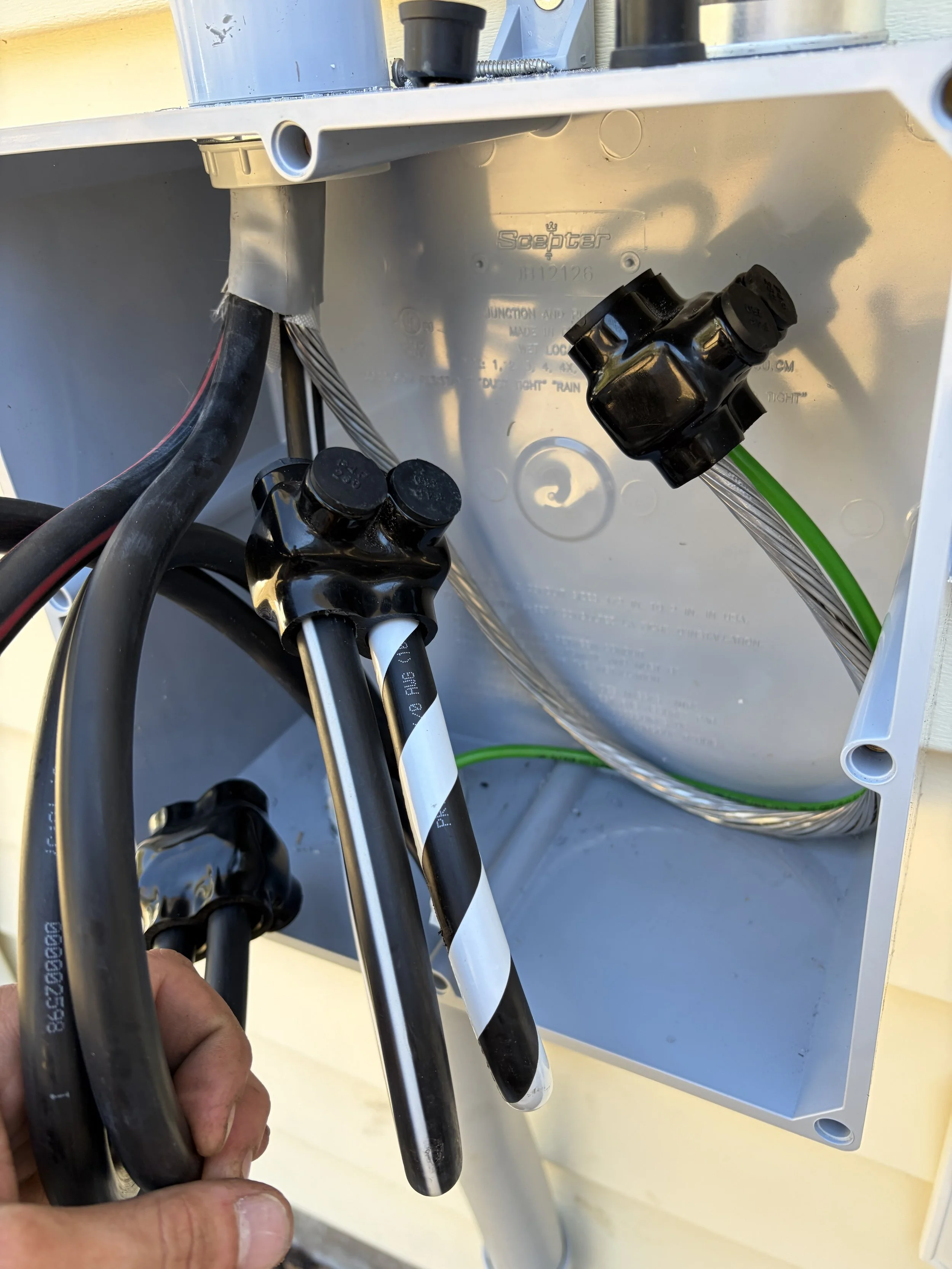 Close-up of an electrical box with black conduit fittings, electrical wires, and metal tubing inside.