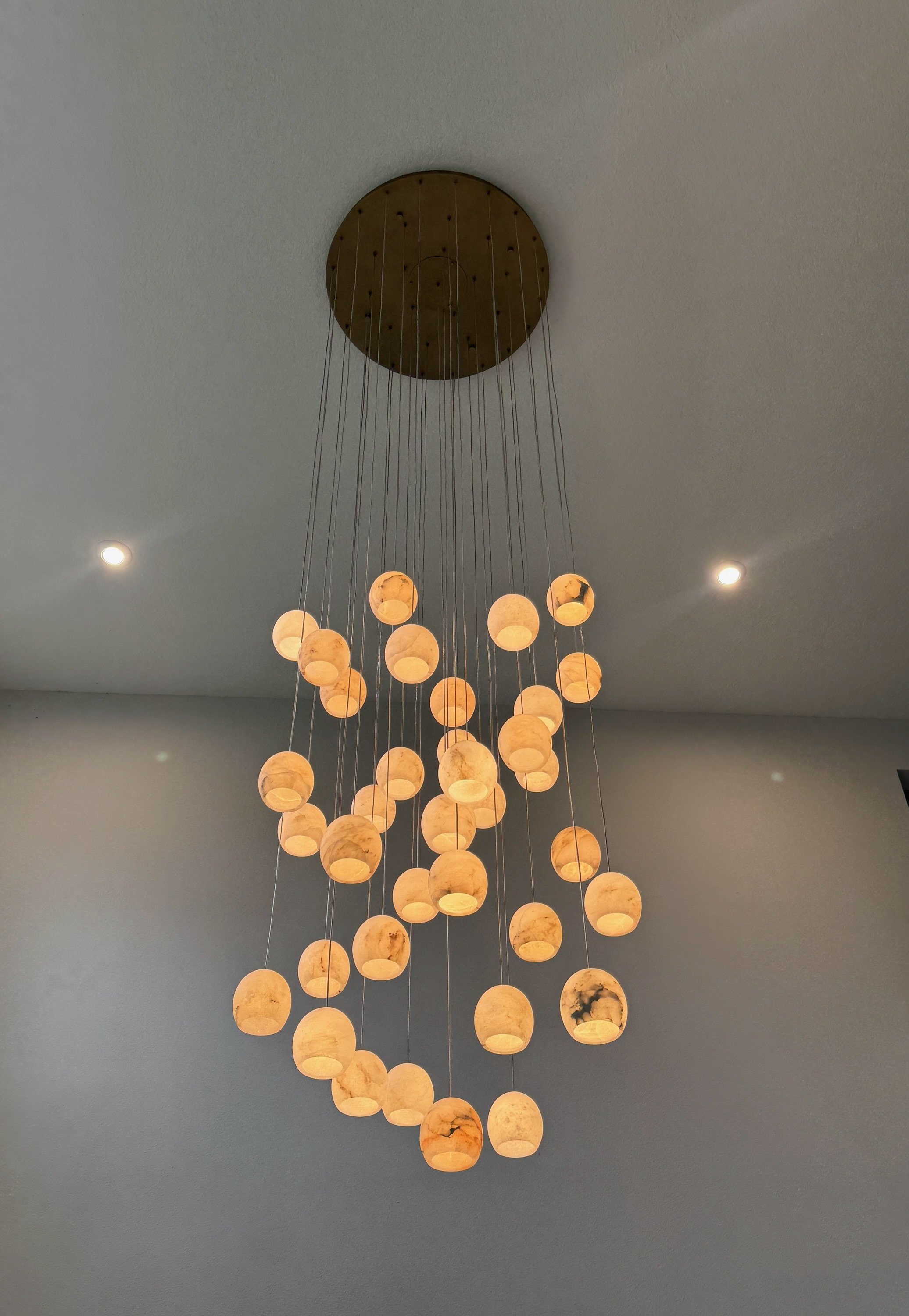 A modern chandelier with multiple round, marble-like globes hanging from thin wires attached to a circular ceiling mount.