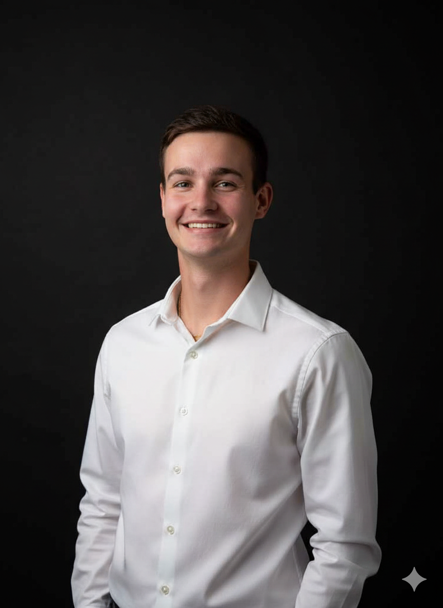 A young man in a green shirt and black beanie smiling against a black background taking a selfie.