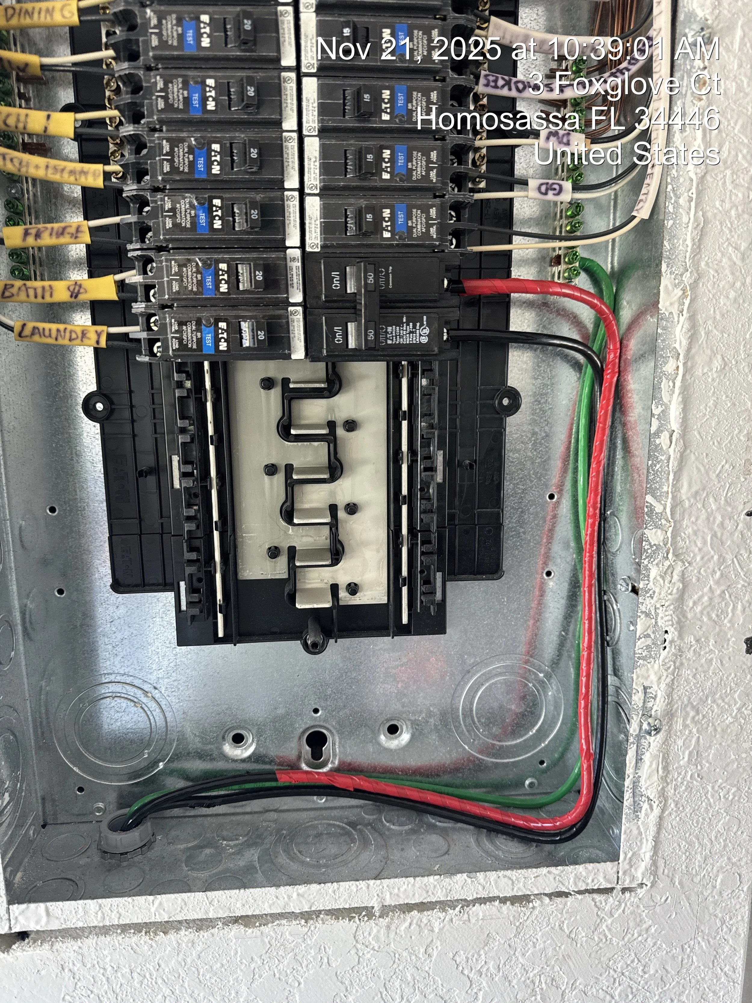 Electrical breaker panel with labeled circuit breakers for bathroom, laundry, and kitchen, with colored wiring connected inside a metal box.