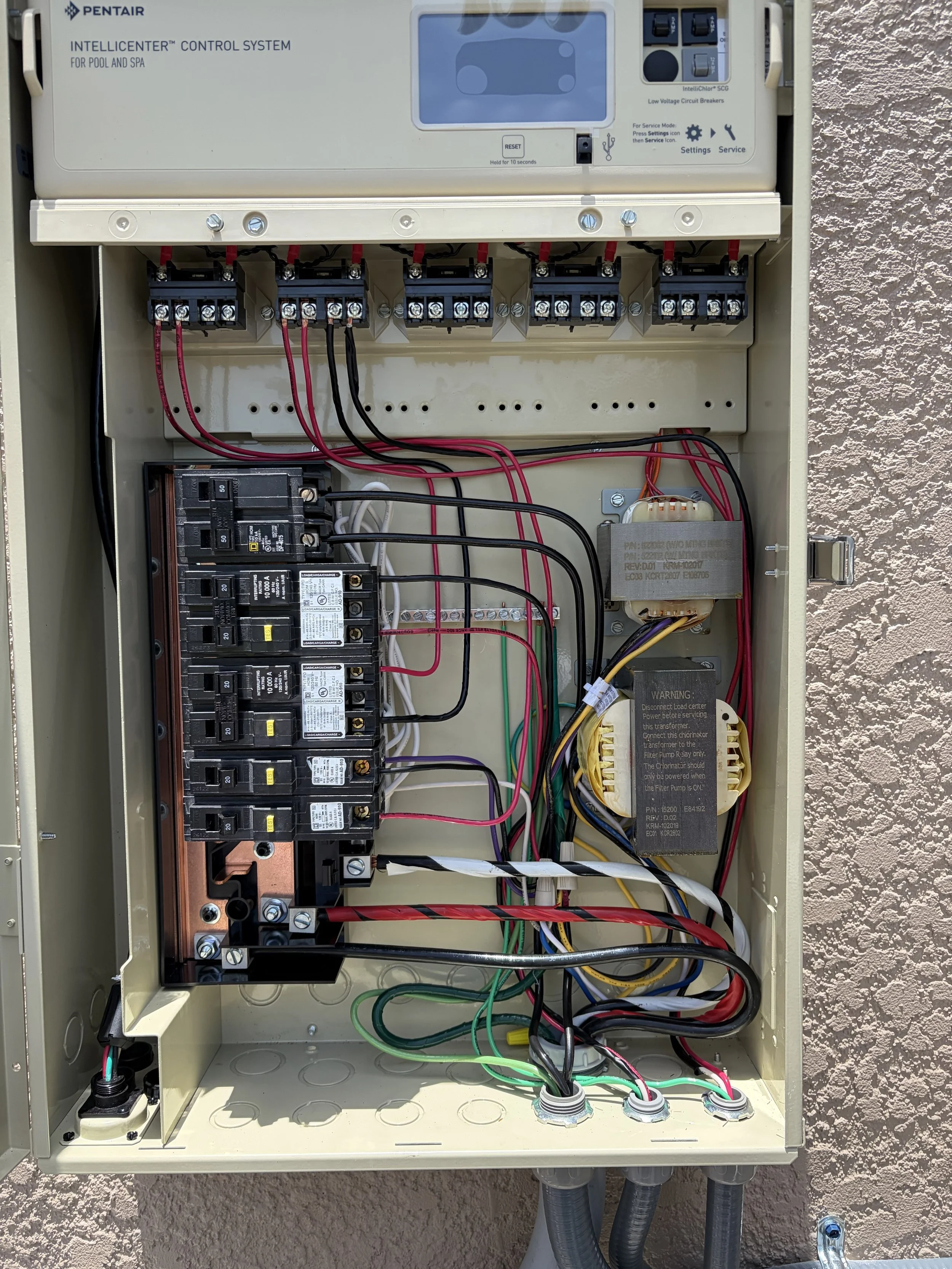 Open electrical control panel with wires and switches, labeled 'Pentair IntelliCenter Control System for Pool and Spa'.