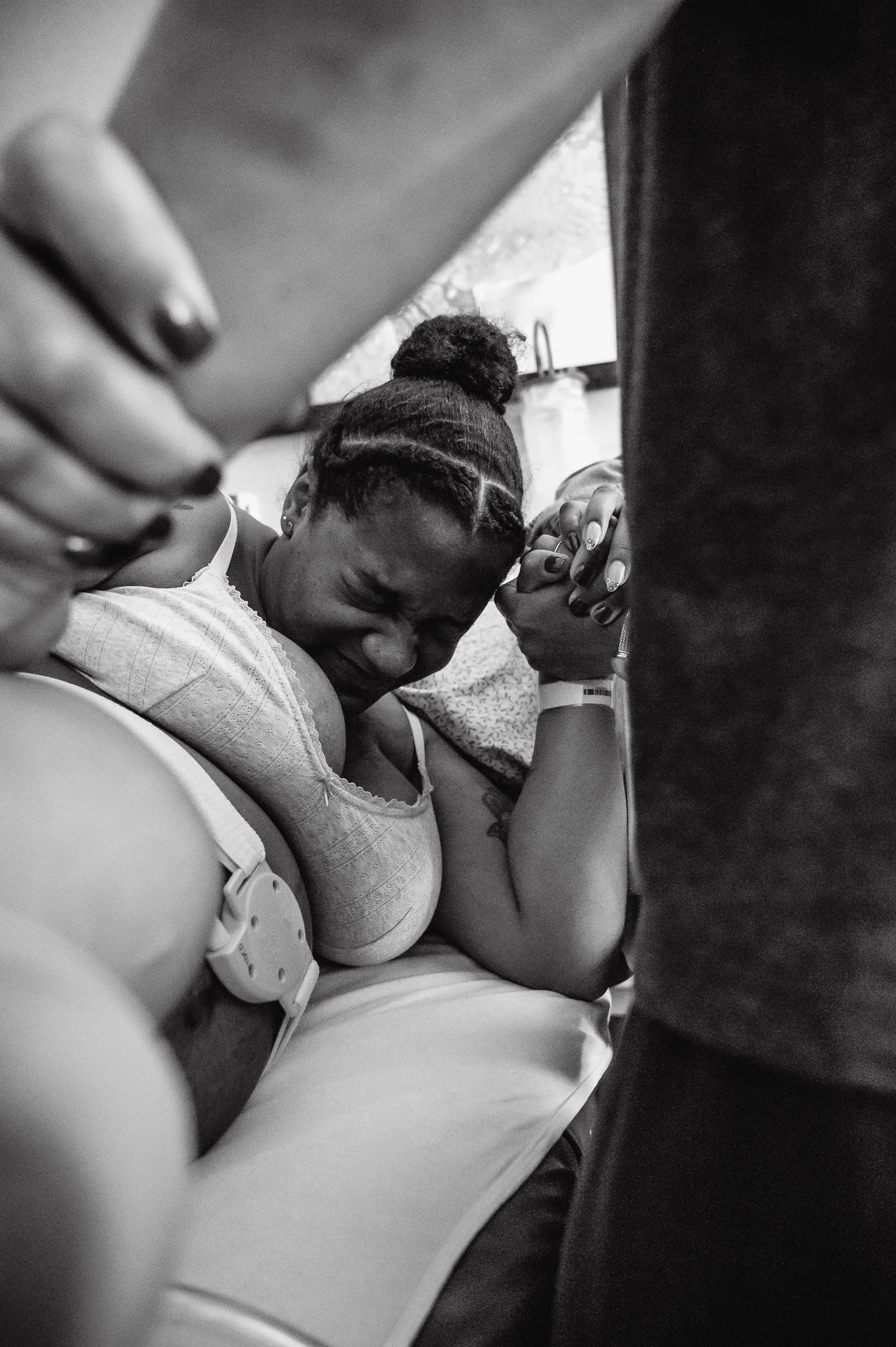 A woman pushing with her eyes closed and hands clasped together, surrounded by people.