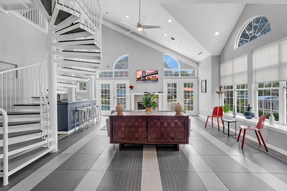 Bright modern living space with large windows, a spiral staircase, and minimalist furniture