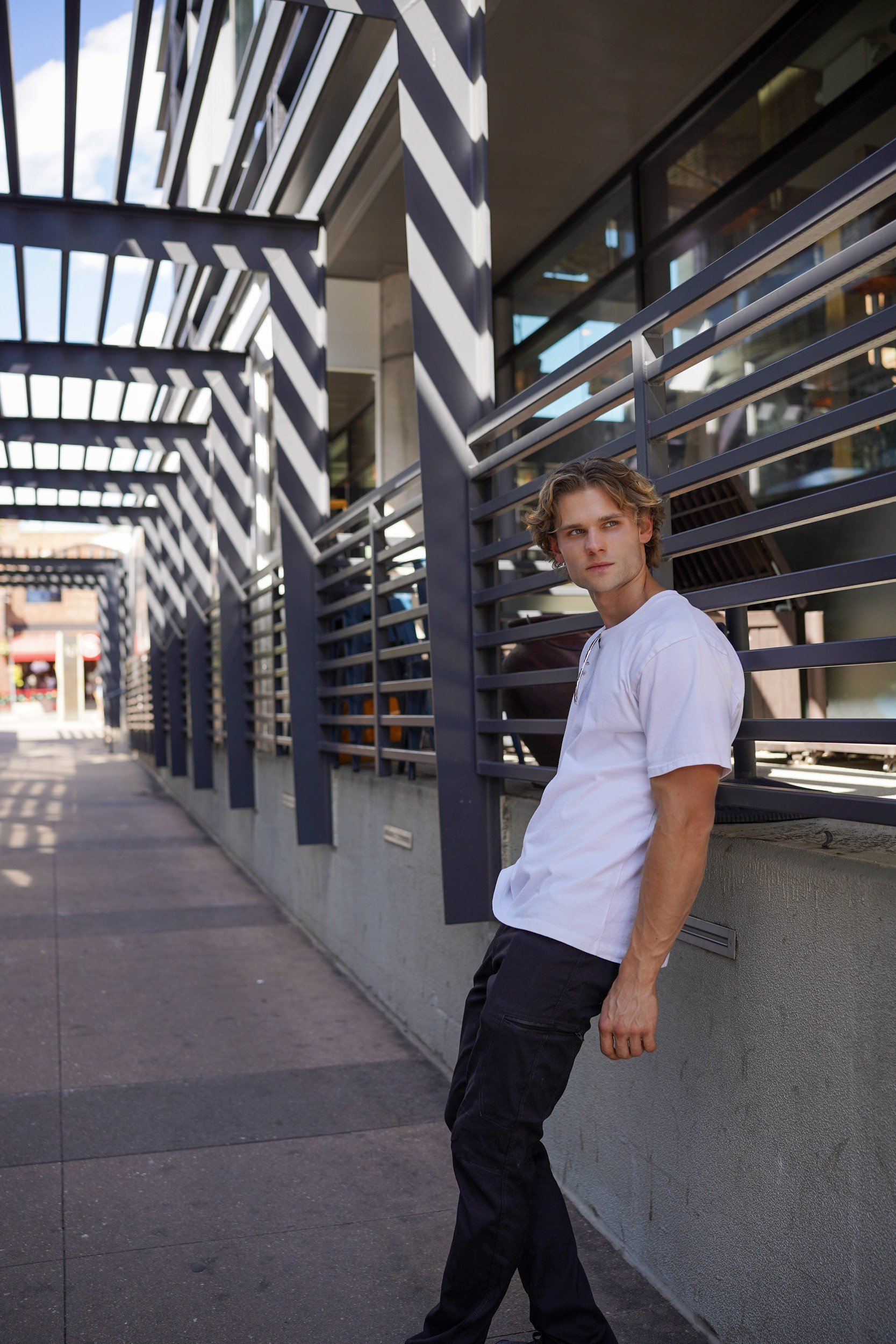 Stepan Salomatin in a white T-shirt beside an urban metal railing