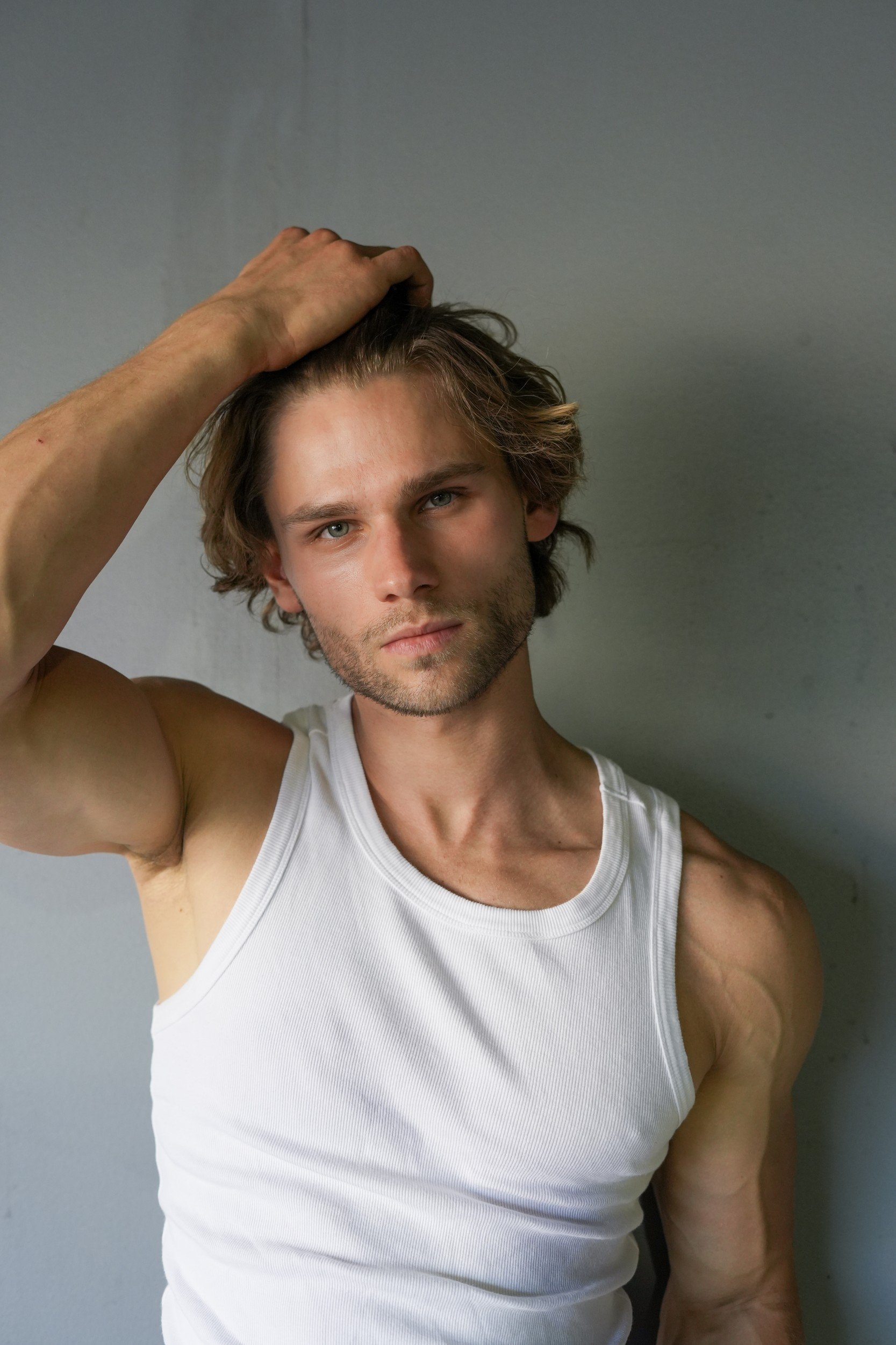 Stepan Salomatin in a white tank top with one hand in his hair