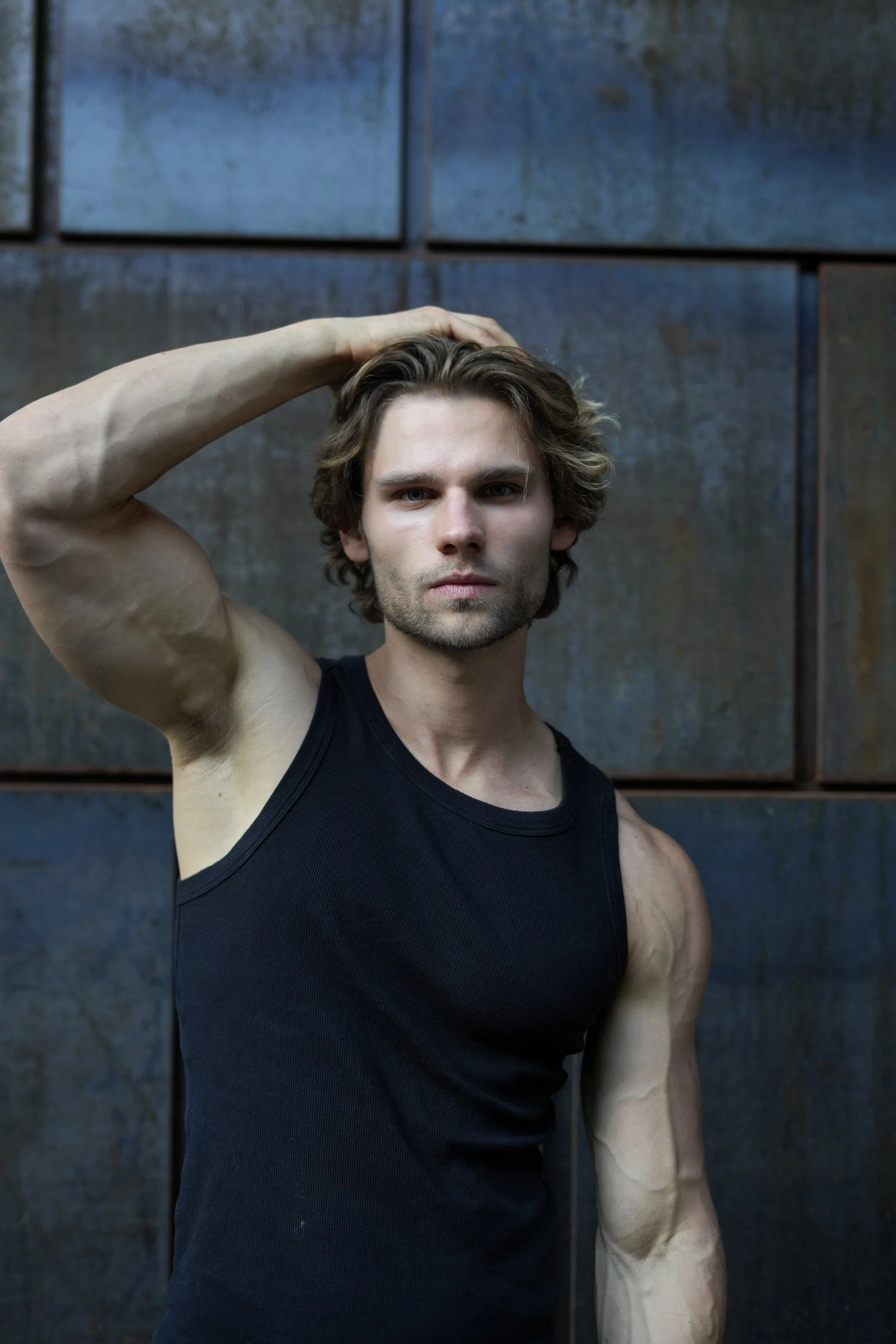 Stepan Salomatin in a black tank top against a dark metal wall