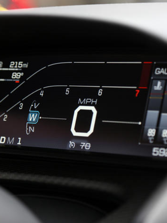 Car dashboard displaying 215 miles remaining, 89°F temperature, speed at 0 MPH, and navigation directions.