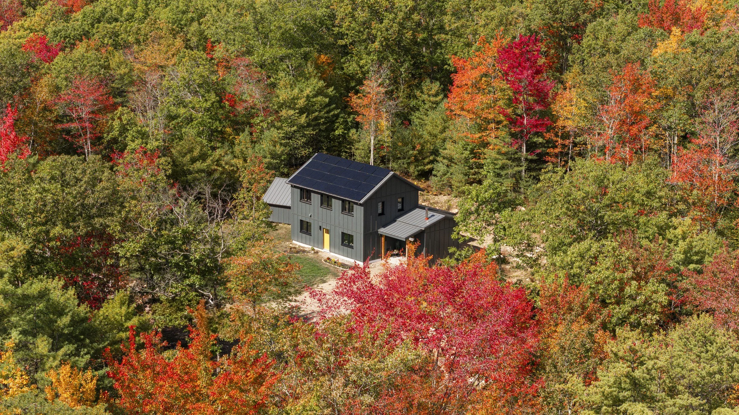 Aerial view of the rooftop solar array and surrounding autumn forest.