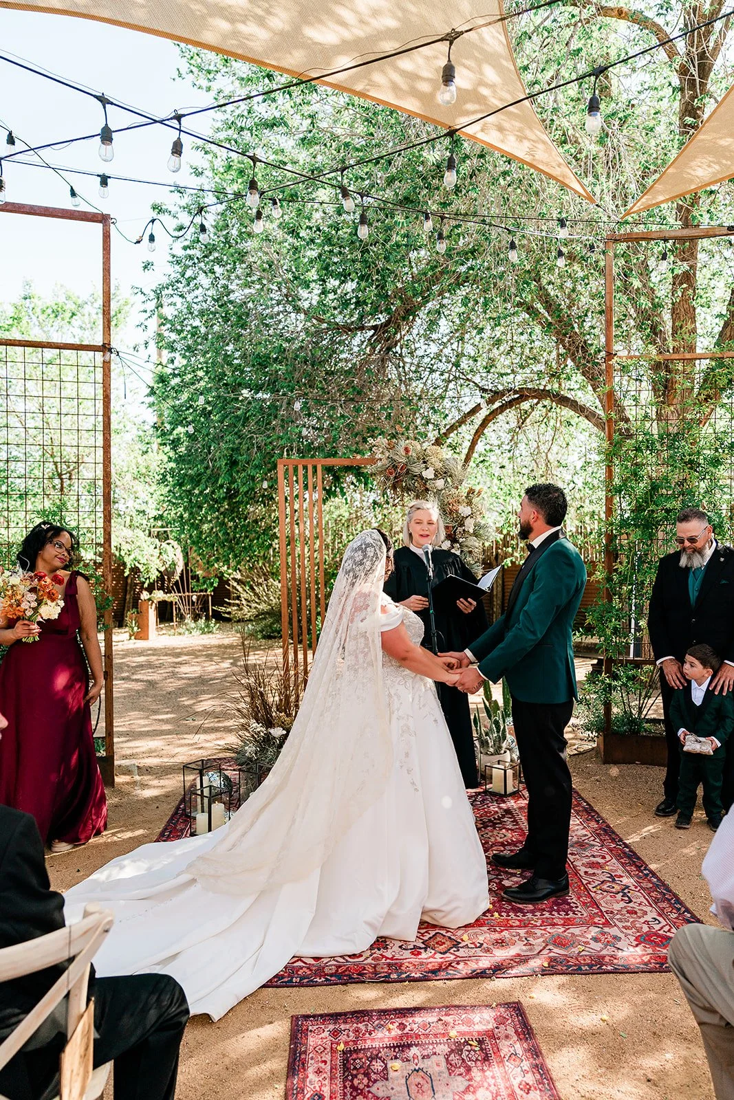 Outdoor Desert Wedding in Santa Fe, New Mexico. Cacti, Boho wedding design, bride in dramatic cathedral veil, jewel tones and trees.