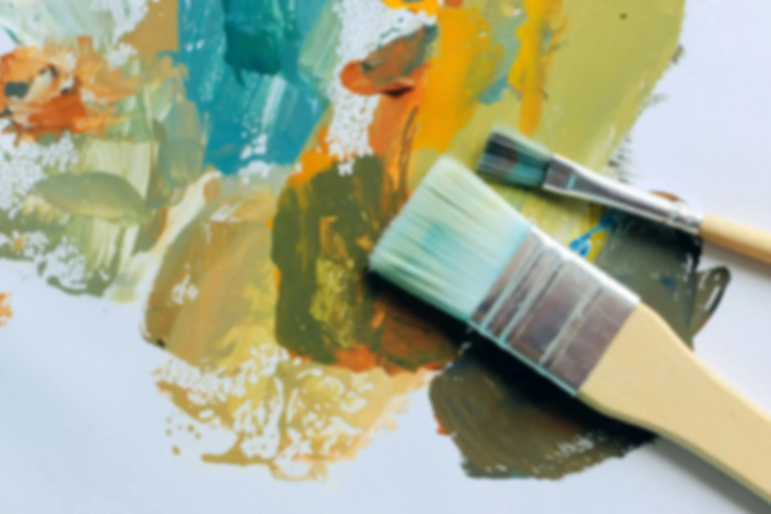 Close-up of a paintbrush resting on a colorful abstract painting with vibrant yellow, green, blue, orange, and black brushstrokes.