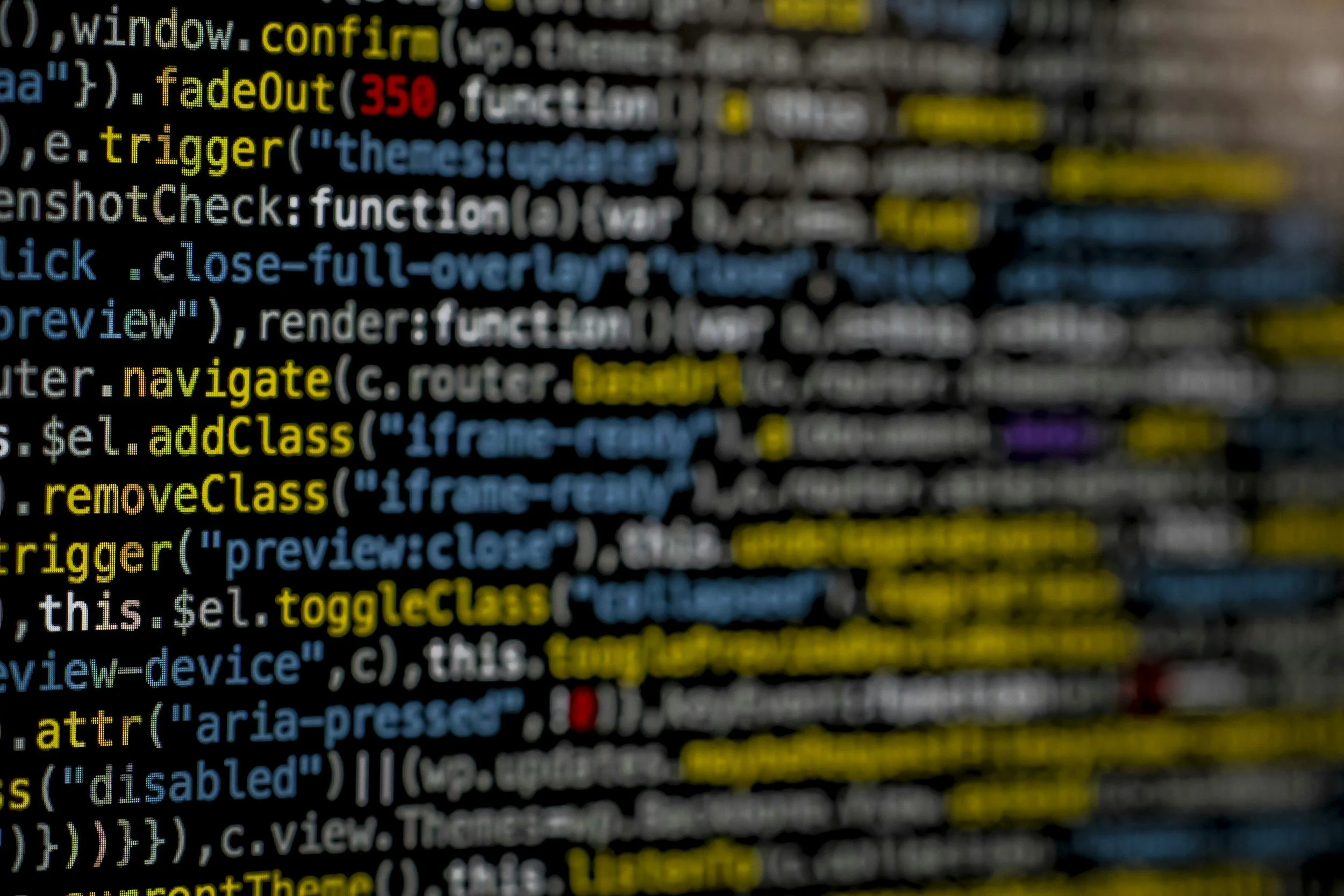 Close-up of computer code displayed on a screen, with highlighted keywords such as "confirm", "fadeOut", "navigate", "addClass", and "toggleClass" in yellow, and other code elements in various colors.