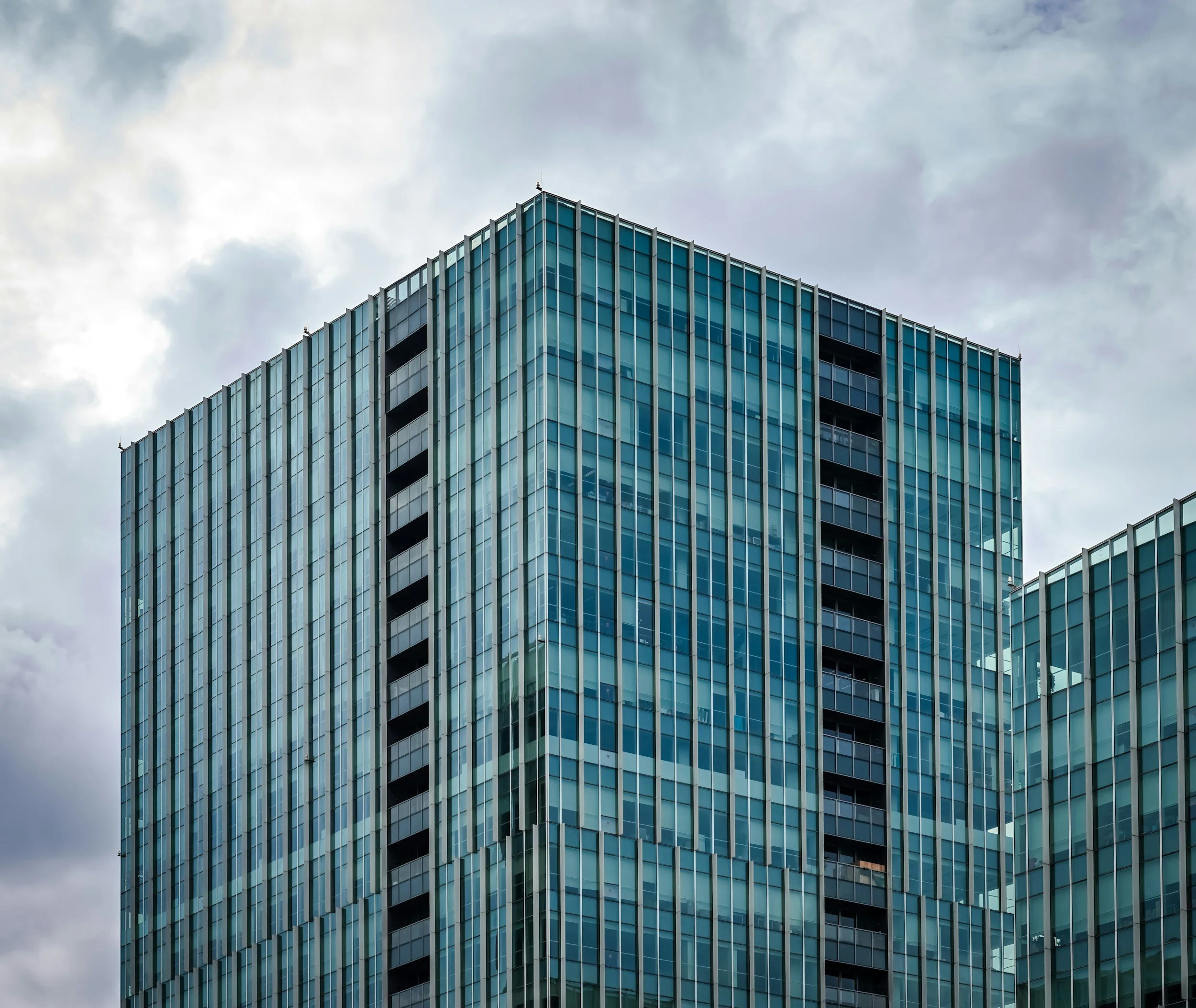 Modern glass skyscraper reflecting cloudy sky