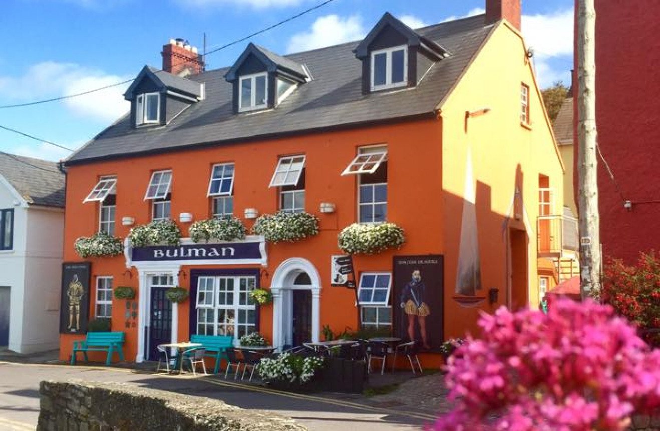 Colorful orange building with flower boxes, outdoor seating, and a sign that reads 'Bulman'.