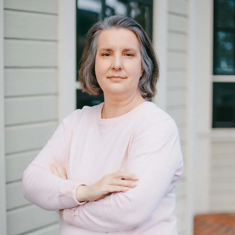 Woman in a pick shirt smiles at the camera.