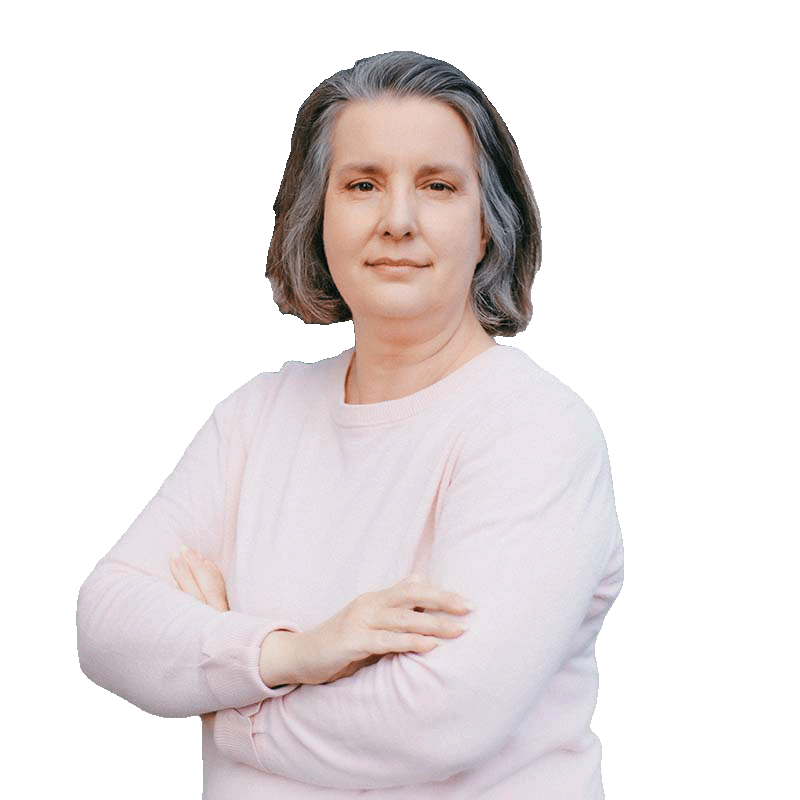 A woman wearing a light pink sweater, crossing her arms and looking at the camera against a white background.