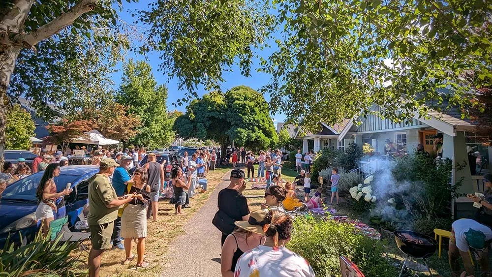 Tacoma's Porchfest with people standing in front yards watching a band while a person grills hotdogs