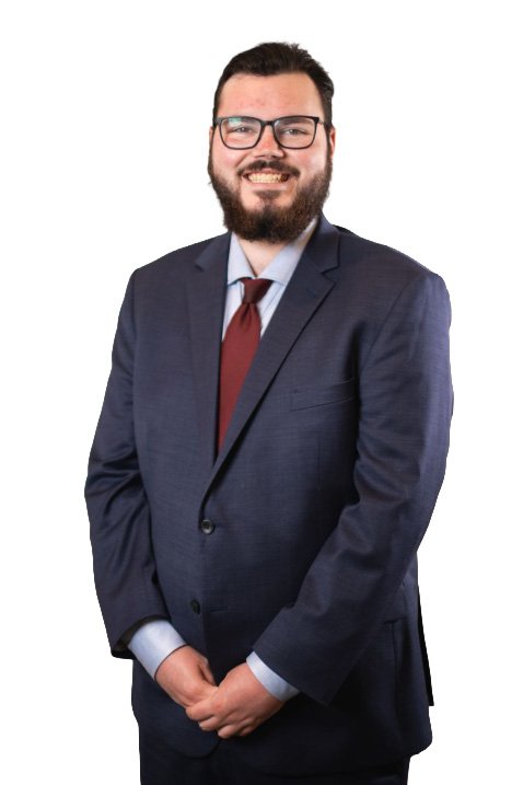 Man in a dark blue suit with glasses and a beard, smiling at the camera