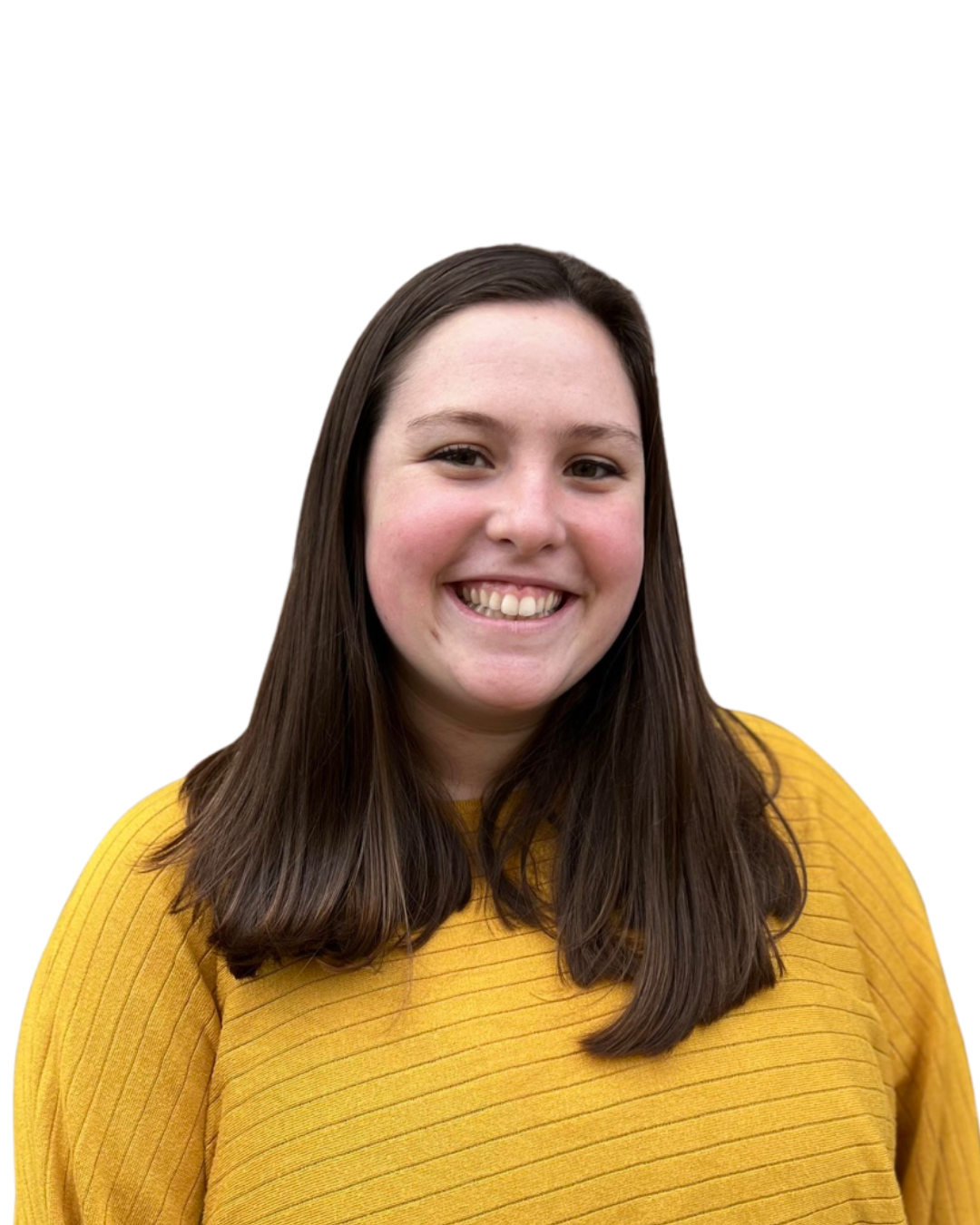 Person in a yellow sweater smiling in front of a multicolored brick wall.