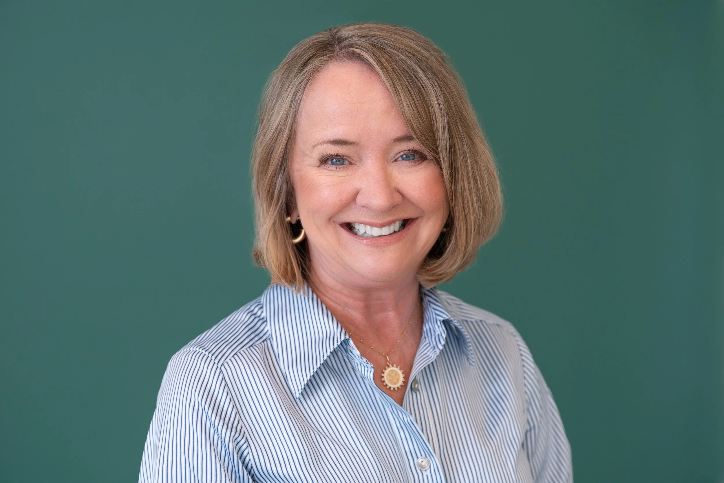 Jill Graham standing in her kitchen wearing an orange blazer and smiling