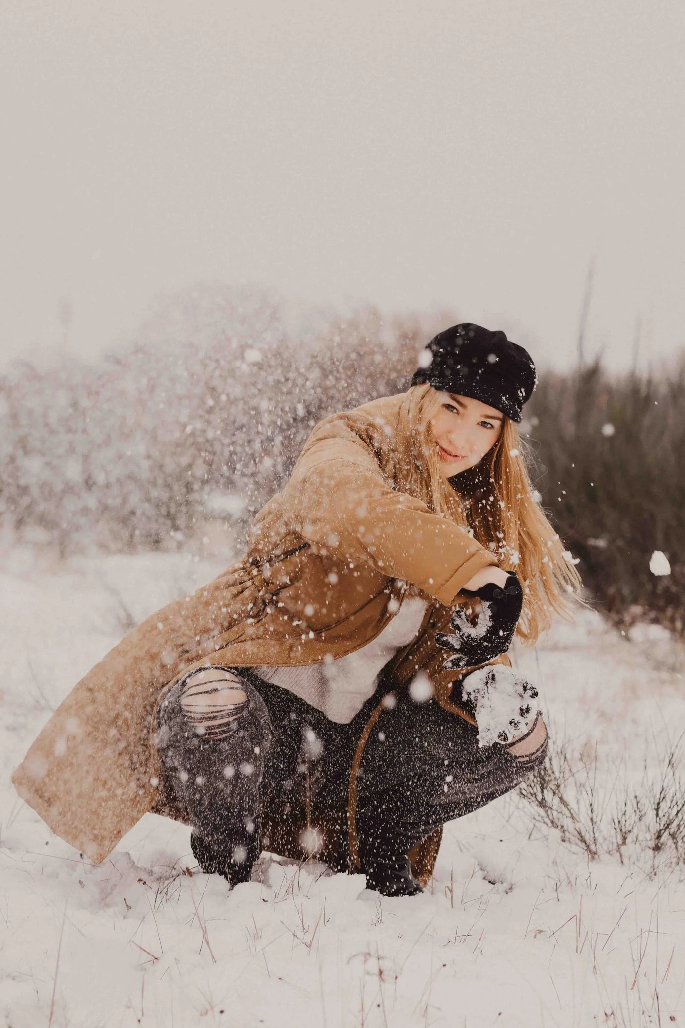 Outdoor-Portrait einer jungen Frau im Winter, die im Schnee spielt in einer Winterlandschaft, bearbeitet mit Hey Poly Lightroom Preset Winter