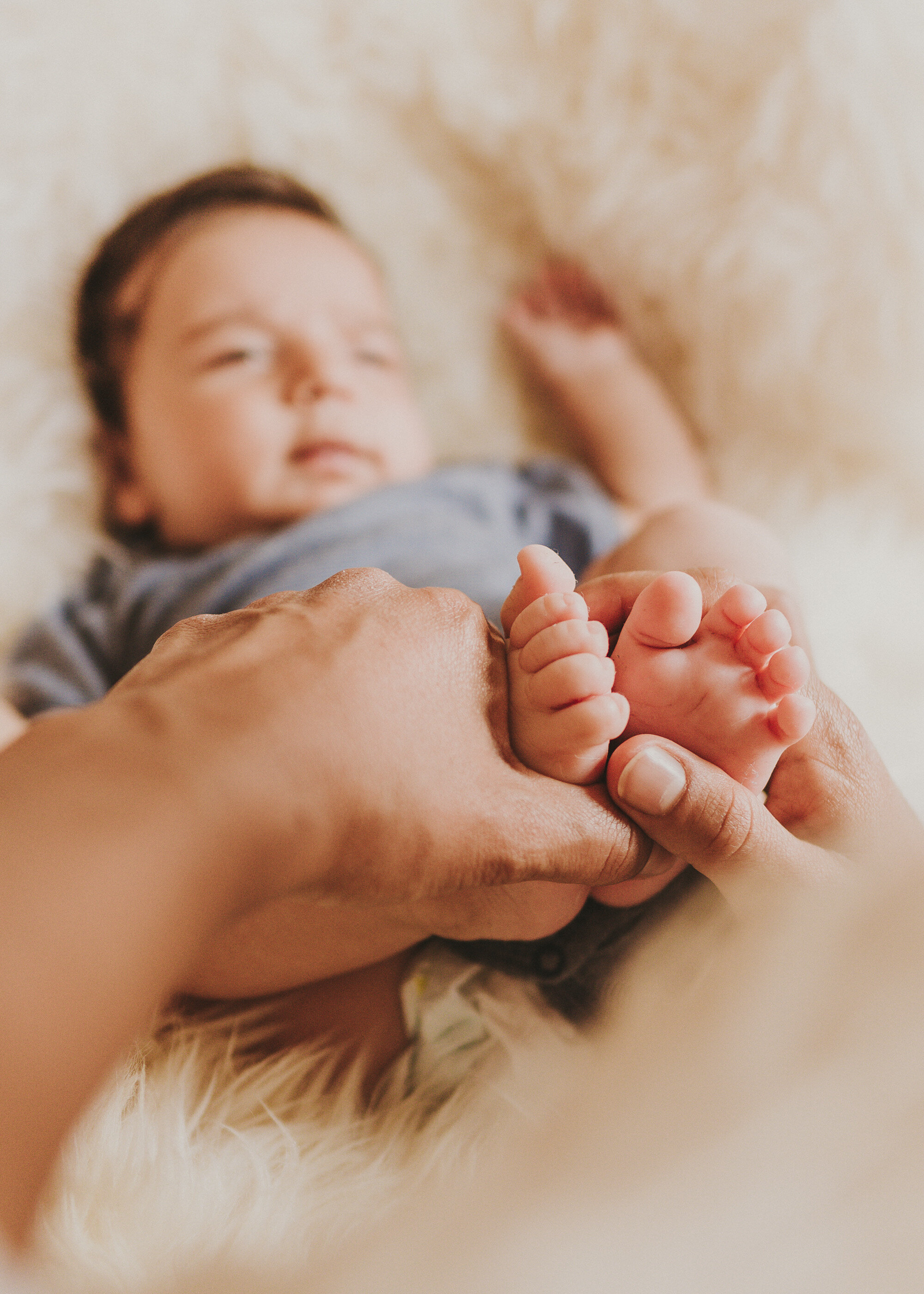 Kleine Babyfüße in den Händen eines Elternteils mit natürlichen Hauttönen